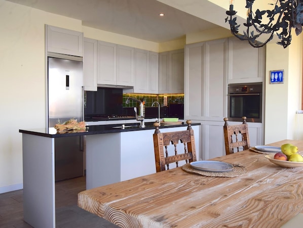 Una cucina moderna con mobili bianchi, un'isola centrale e un tavolo da pranzo con sedie.