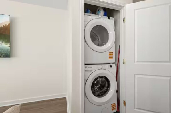 A laundry room with two stacked washing machines, a door, and a wall-mounted picture. - The Royal Inn (Lafayette)