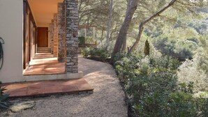 Un bâtiment moderne avec une façade en pierre, une porte en bois et un chemin de gravier menant à un espace extérieur couvert.