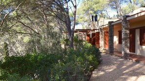 Un bâtiment doté de piliers en pierre, de portes en bois et d’un chemin de gravier menant à l’entrée.