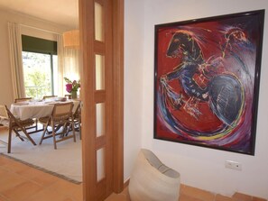 A dining area with a table set for four, a chair, and a vase with flowers. - Casa Santani (Begur, Sa Tuna) (Sa Tuna, Begur)
