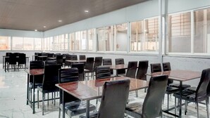 A spacious indoor area with rows of tables and chairs, large windows, and a polished floor. - Deluxe Hinjewadi Corporate Stays (Paud)