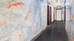 A hallway with marble walls and a black floor, leading to an elevator. - Deluxe Hinjewadi Corporate Stays (Paud)