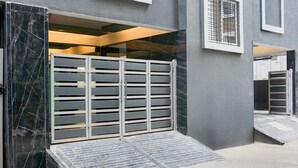 A gated entrance with a ramp leading to a building with a grey exterior and a tiled floor. - Deluxe Hinjewadi Corporate Stays (Paud)