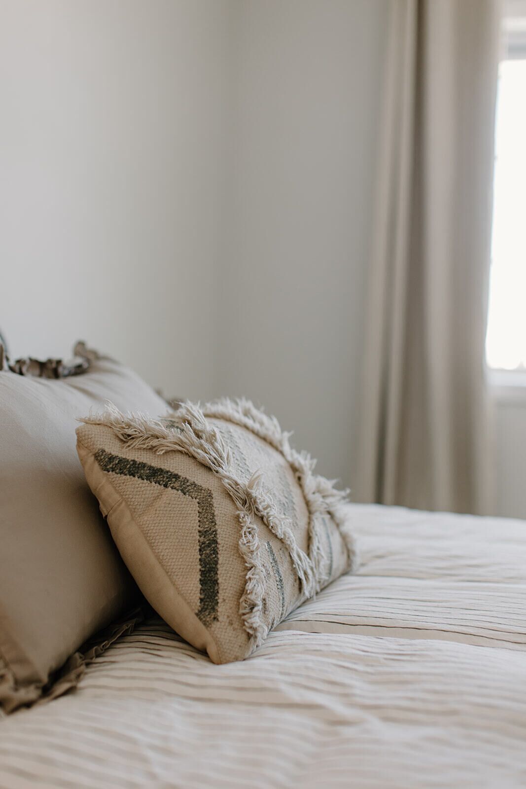 A bed with two pillows, one with a textured pattern and the other with a simple design.