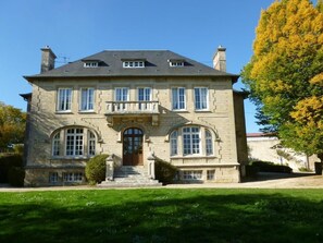 A large, two-story stone building with a symmetrical facade, multiple windows, and a central entrance. - La Chambre au Château (Pernant)