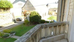 Un balcó amb barana de pedra que fa vedar un jardí i un carrer.