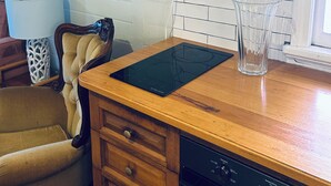 Une cuisine avec un plan de travail en bois, un lave-vaisselle, un crédence carrelée de carreaux blancs, un tableau encadré représentant une jetée et une lampe.