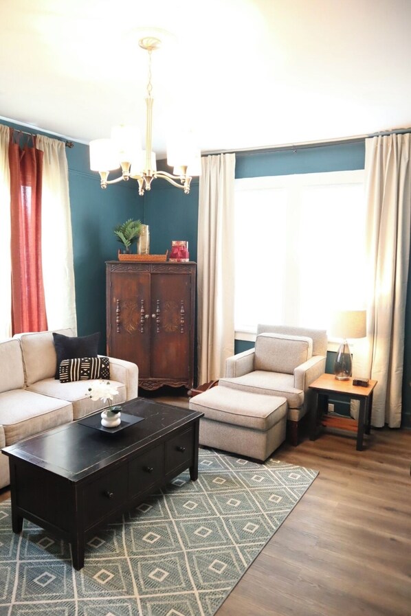 A living room with a sofa, armchair, coffee table, and a cabinet.