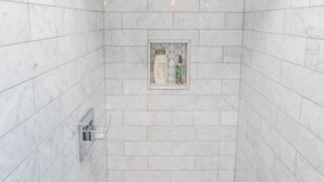 Une douche avec une porte en verre et un sol carrelé.