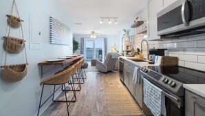 Una cocina moderna con microondas, horno y comedor con sillas de mimbre.