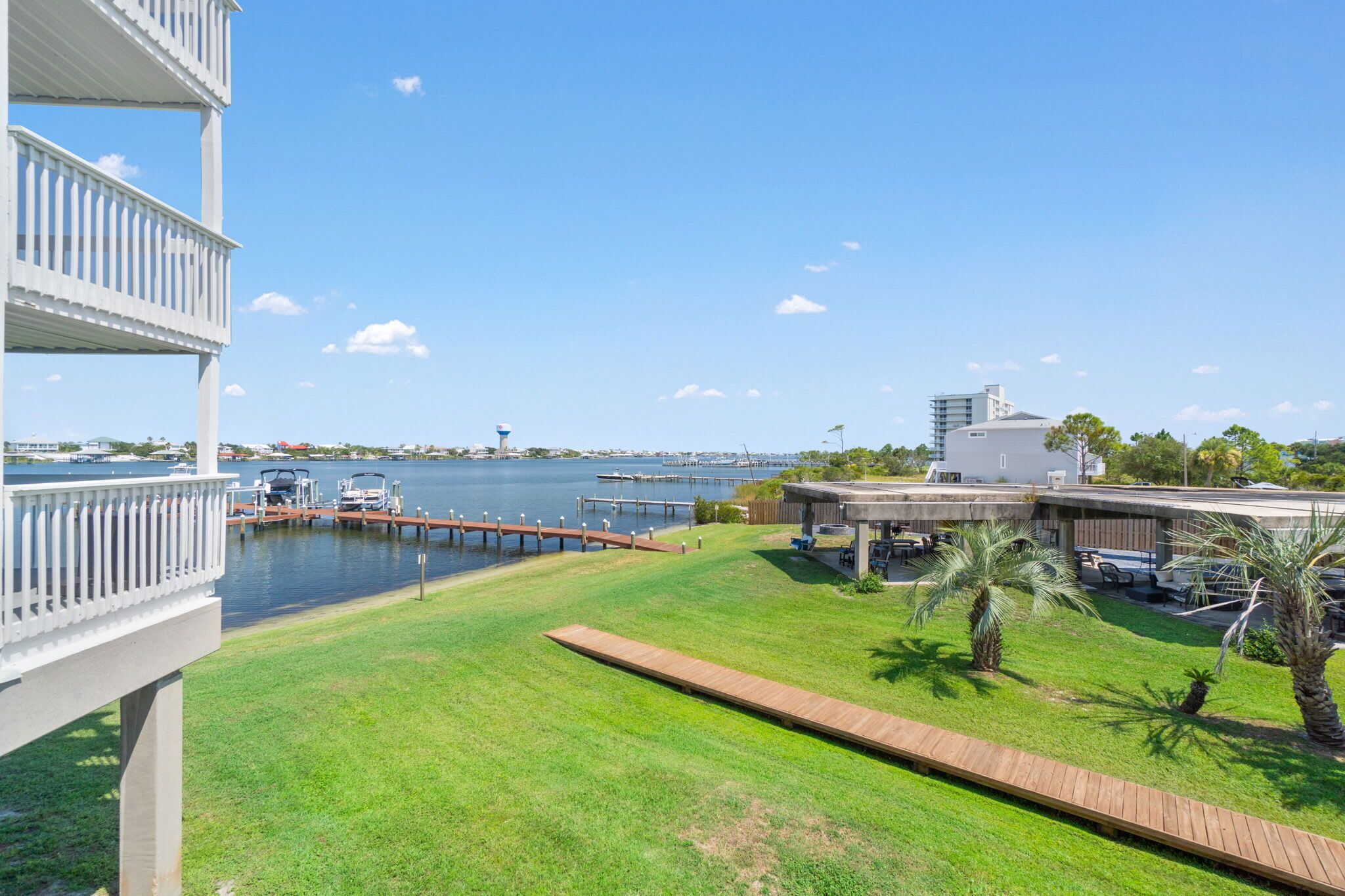 A waterfront property with a grassy lawn, a wooden deck, and a dock extending into the water.