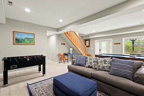 A living room with a pool table, a foosball table, a sofa, and a staircase. - Open Living, Fall Views, Hot Tub, Near Ski Slopes (Beech Mountain)