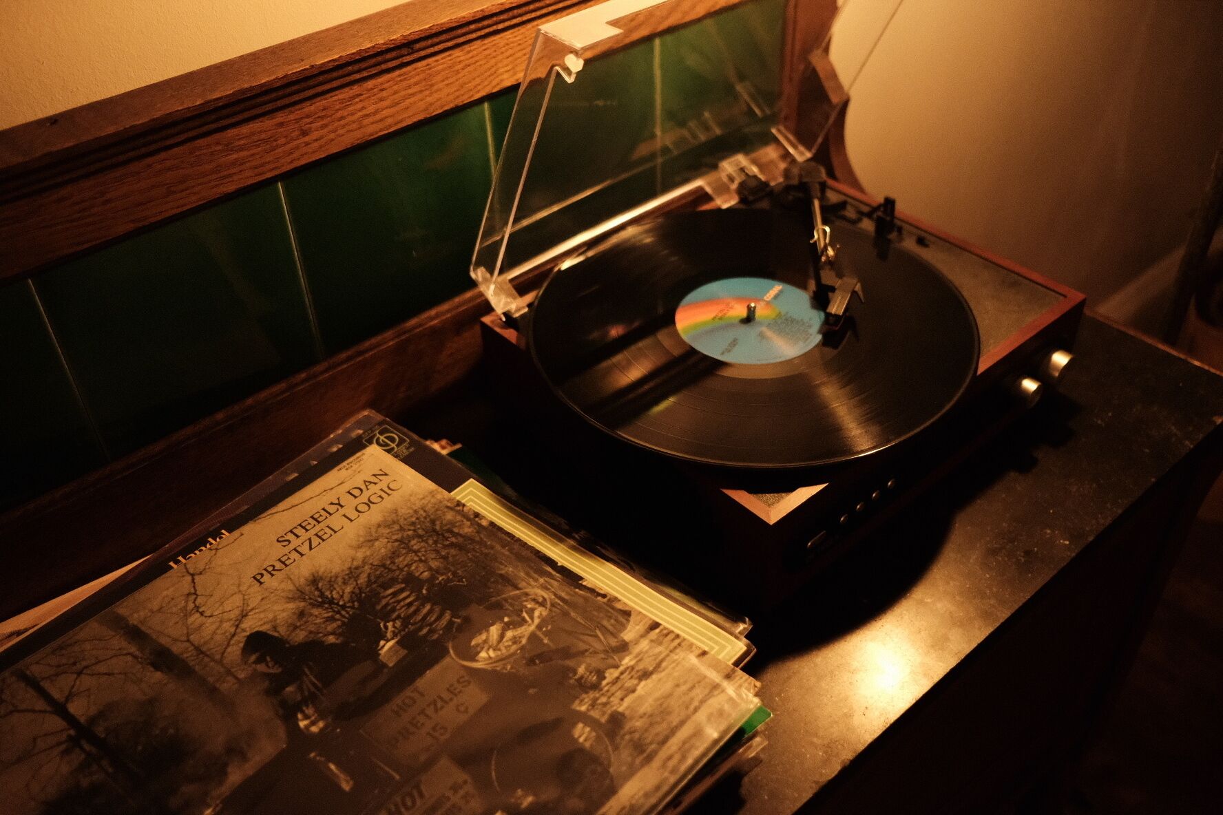 Une platine vinyle avec un disque, une pile de livres et une fenêtre avec un cadre en bois.