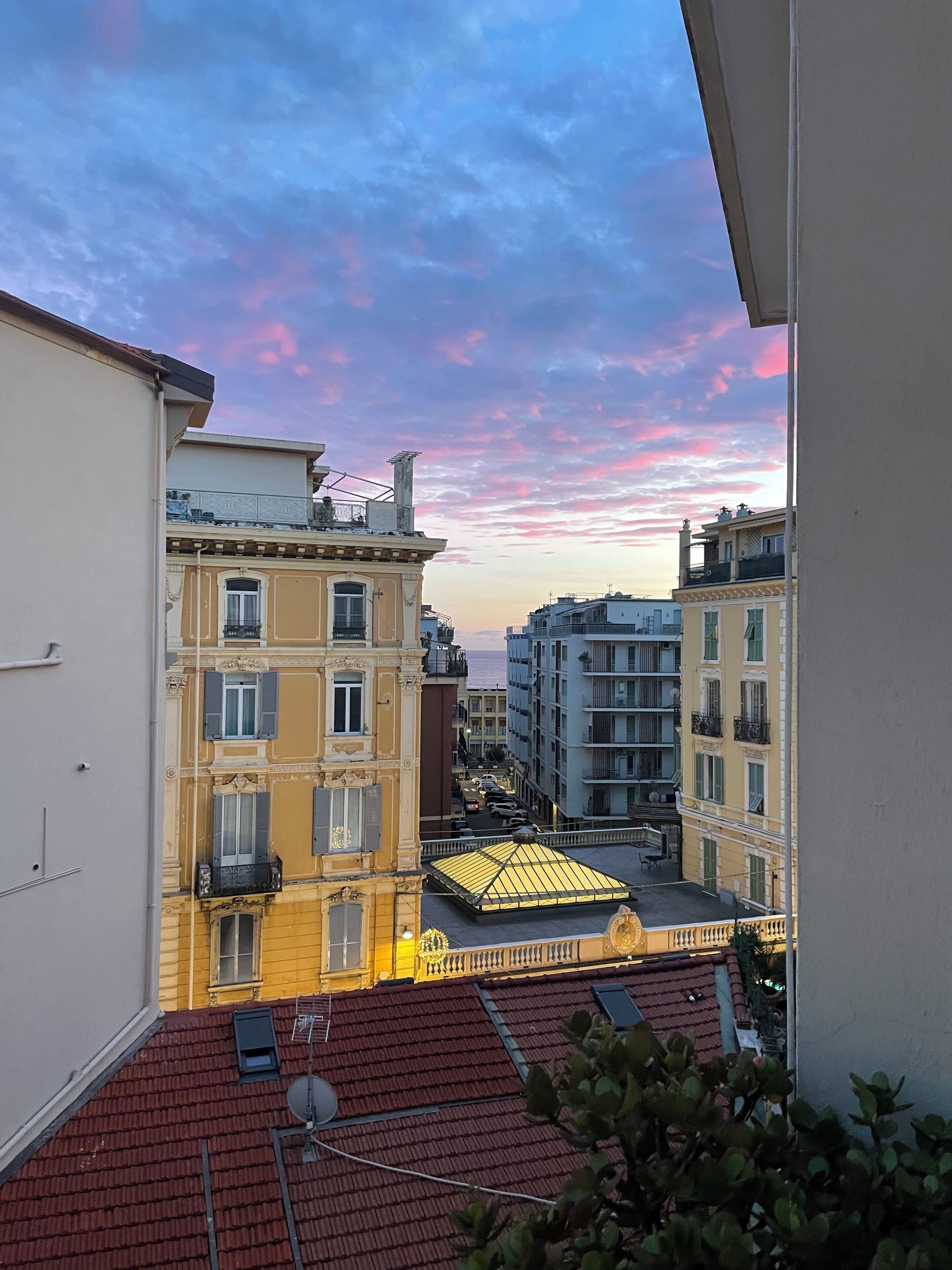 A view of a cityscape with buildings and a sunset sky.