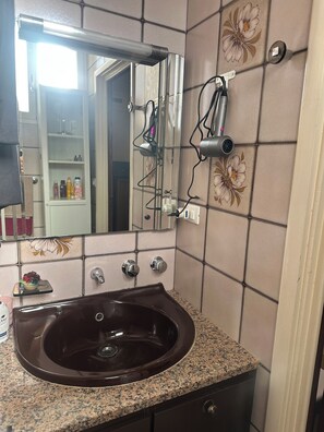A bathroom with a sink, mirror, and tiled walls. - Bright apartment in the heart of San Remo (Sanremo)