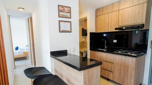 A modern kitchen with wooden cabinets, a black countertop, and a gas stove. - MonteAzul apto con vista a la Cordillera (Armenia)