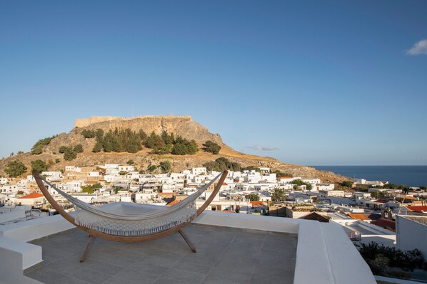 A hammock on a rooftop with a view of a fortified hill and white buildings. - Exclusive Villa Qupi in the center of Lindos separate staff accommodation (Lindos)