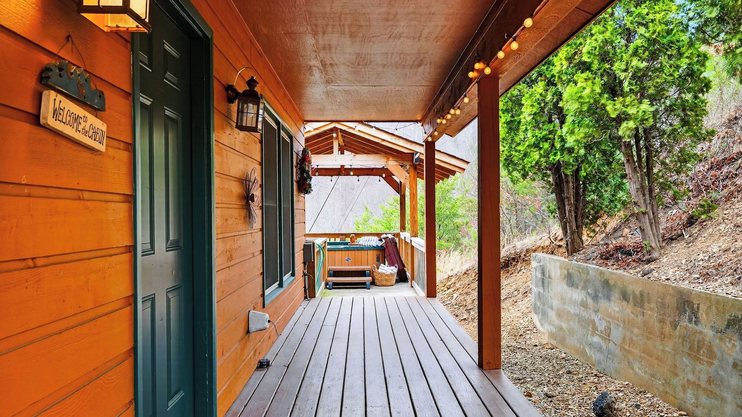 Une cabane en bois avec une véranda, un banc et un jacuzzi.