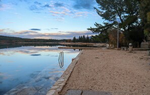 Un paisatge tranquil al costat d'un llac, amb vistes clares a l'aigua, un camí de pedra i una boscadeta.