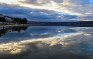 Un llac tranquil amb el reflex del cel, envoltat d'edificis i arbres.
