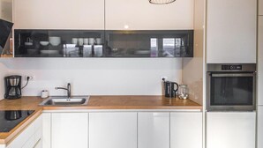 Et moderne køkken med en stålvask, kaffemaskine og et indbygget ovn.