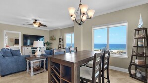 A spacious living area with a dining table, sofas, and a TV. - Stunning corner unit in the heart of Pensacola beach with panoramic views. (Pensacola Beach)