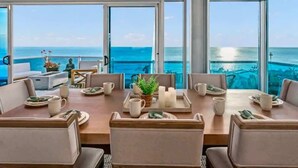 Comedor con vista al océano, ventanas amplias y mesa lista para dos.