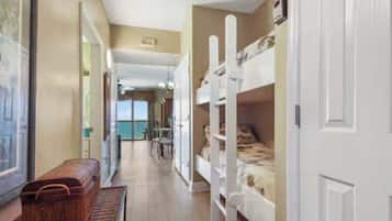 Habitación de hotel con literas, un banco de madera y vista al mar a través de un ventanal amplio.