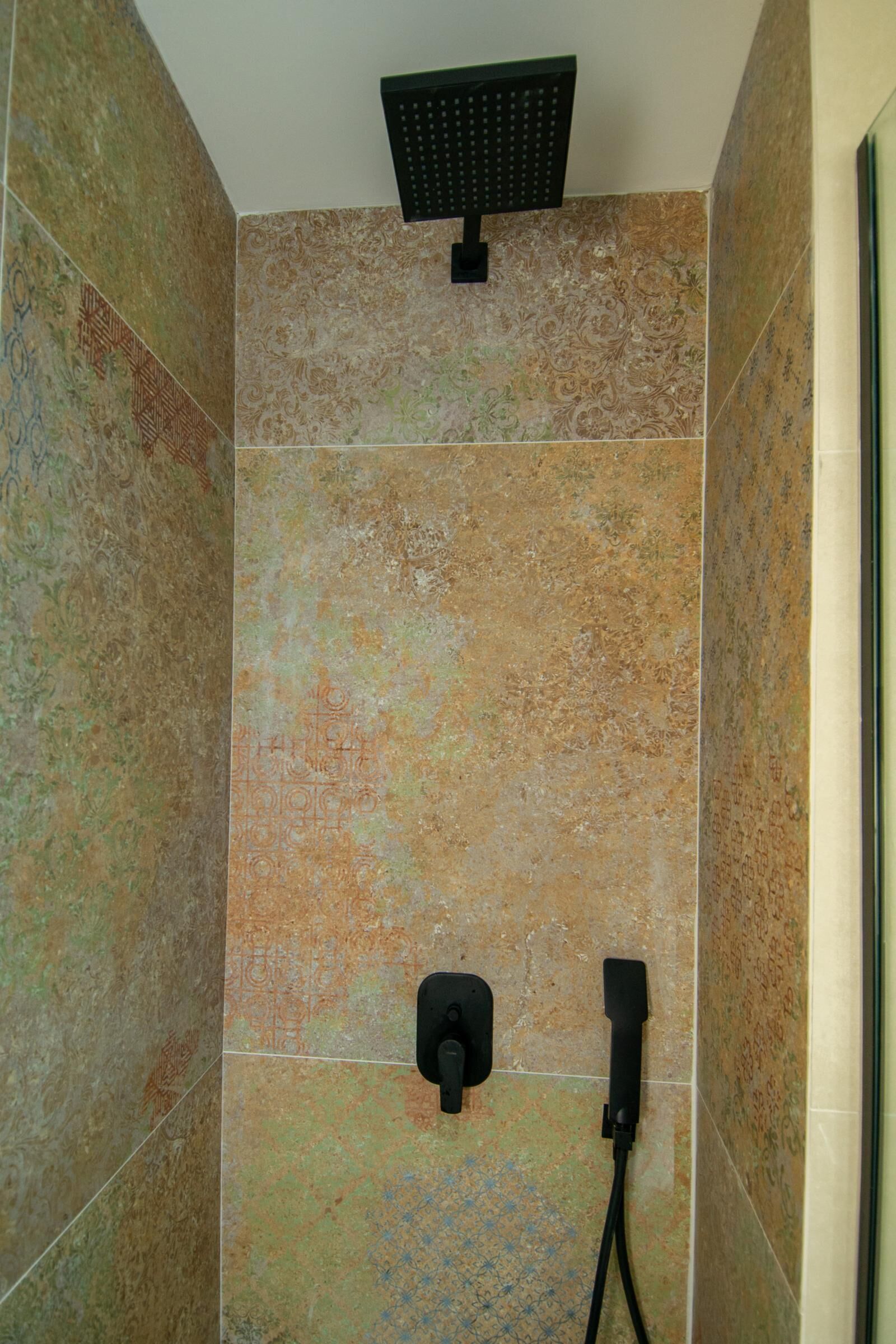 Un área de ducha con ducha de mano y grifería empotrada.