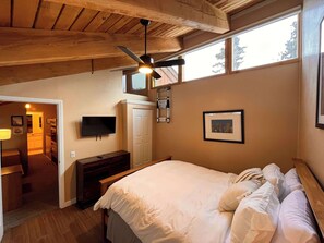 A bedroom with a bed, a ceiling fan, a TV, a wardrobe, and a window. - Cozy Mtn. Condo, Hot Tub, Garage, Dog Friendly (Mammoth Lakes)