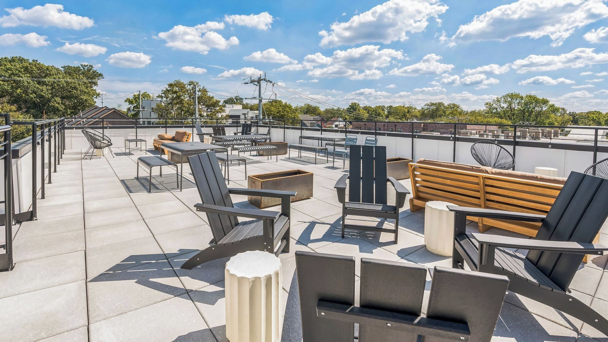 A rooftop terrace with outdoor seating, including chairs and a bench, under a clear sky.