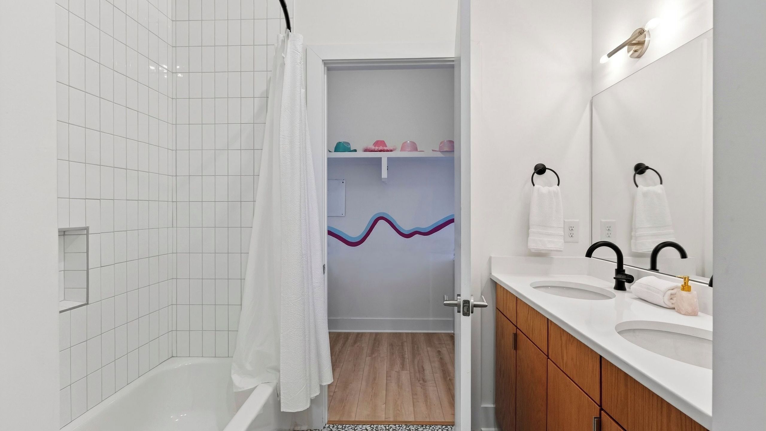 A modern bathroom with a bathtub, a shower curtain, a vanity with a mirror, and a towel rack.