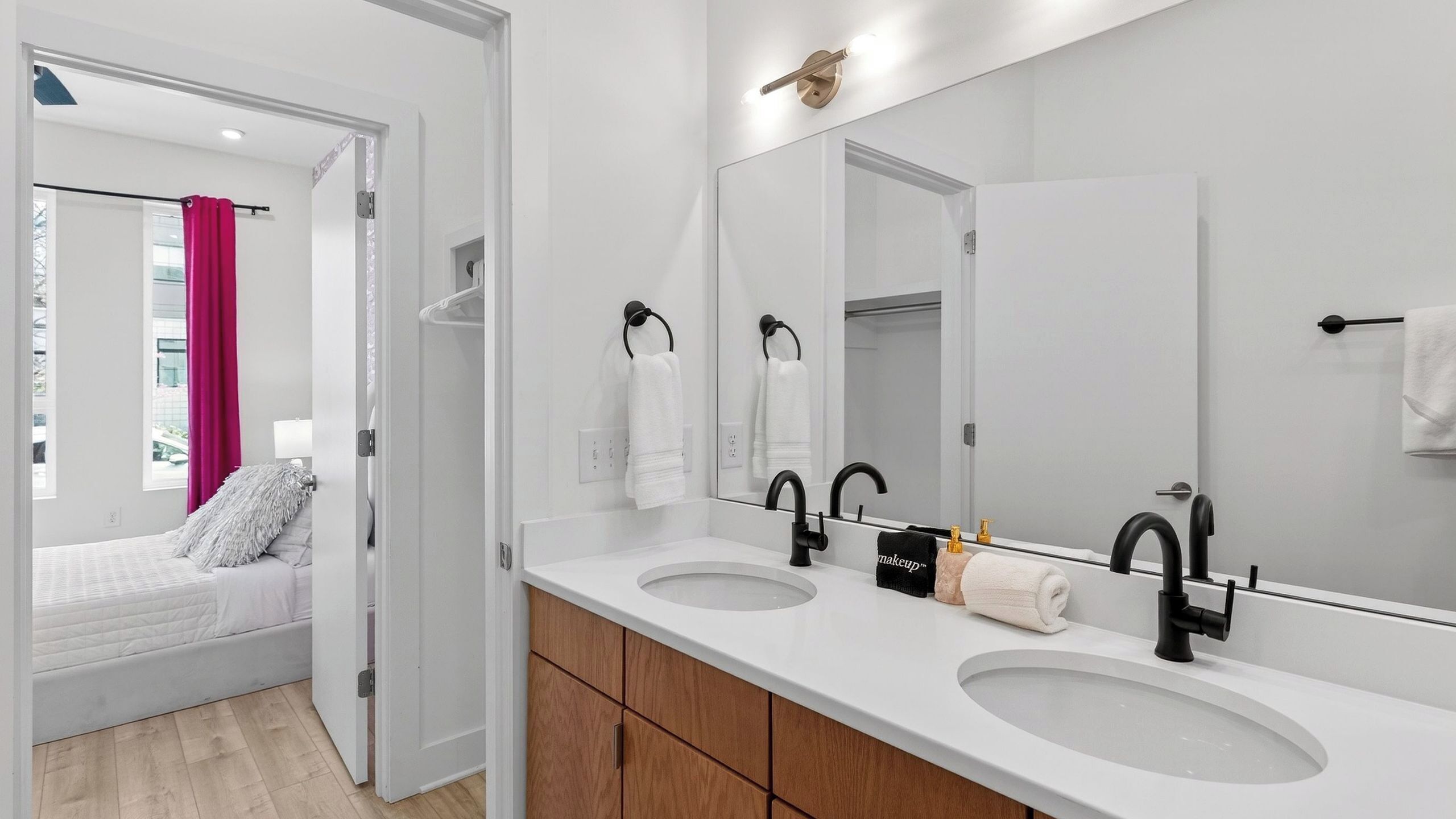 A modern bathroom with two sinks, a large mirror, and a walk-in shower.
