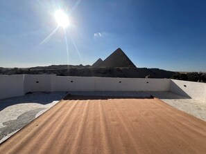 A rooftop terrace with a clear view of pyramids in the distance. - Pyramids View • places (محافظة الجيزة)