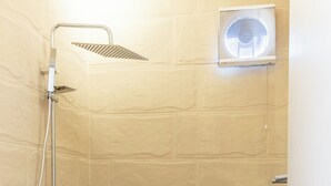 Ett badrum med dusch, toalett och en fläkt för ventilation.
