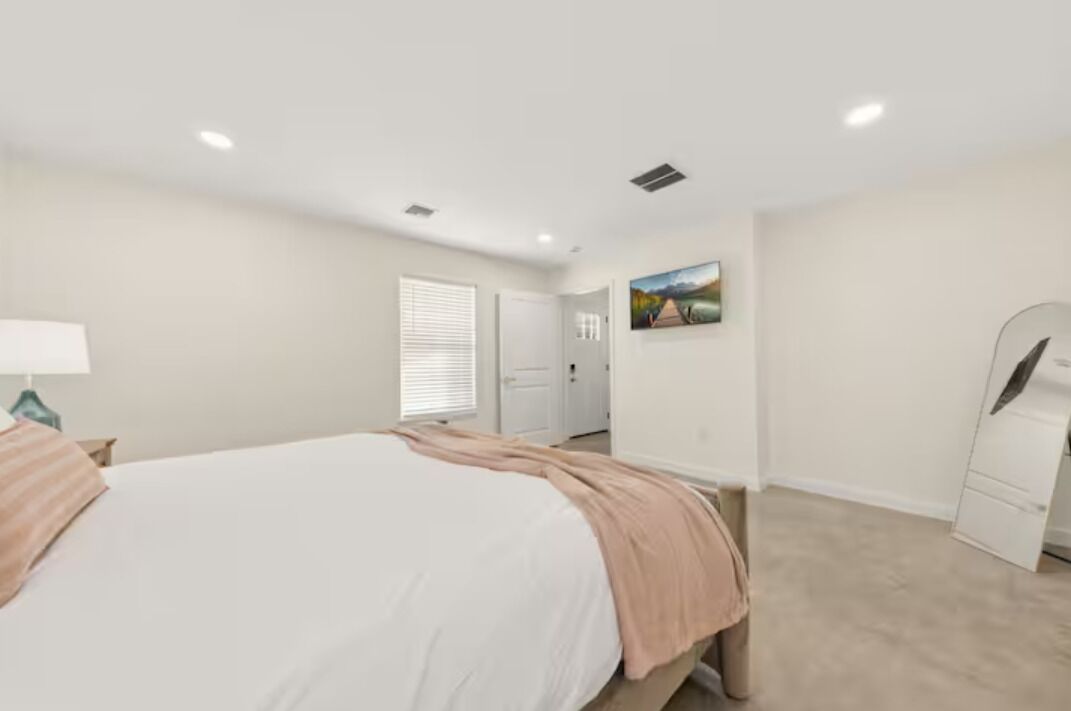 A bedroom with a bed, a dresser, a mirror, and a door leading to another room.