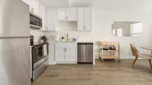 Une cuisine moderne avec des meubles blancs, des appareils en acier inoxydable et un coin repas en bois.