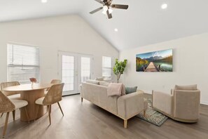 A spacious living area with a round dining table, a sofa, and a painting of a lake. - Canal Inn (Lafayette)