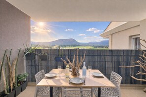A dining area with a table set for four, surrounded by chairs, with a view of a mountainous landscape. - Tropical Escape - Mountain View & Terrace (sarrola)