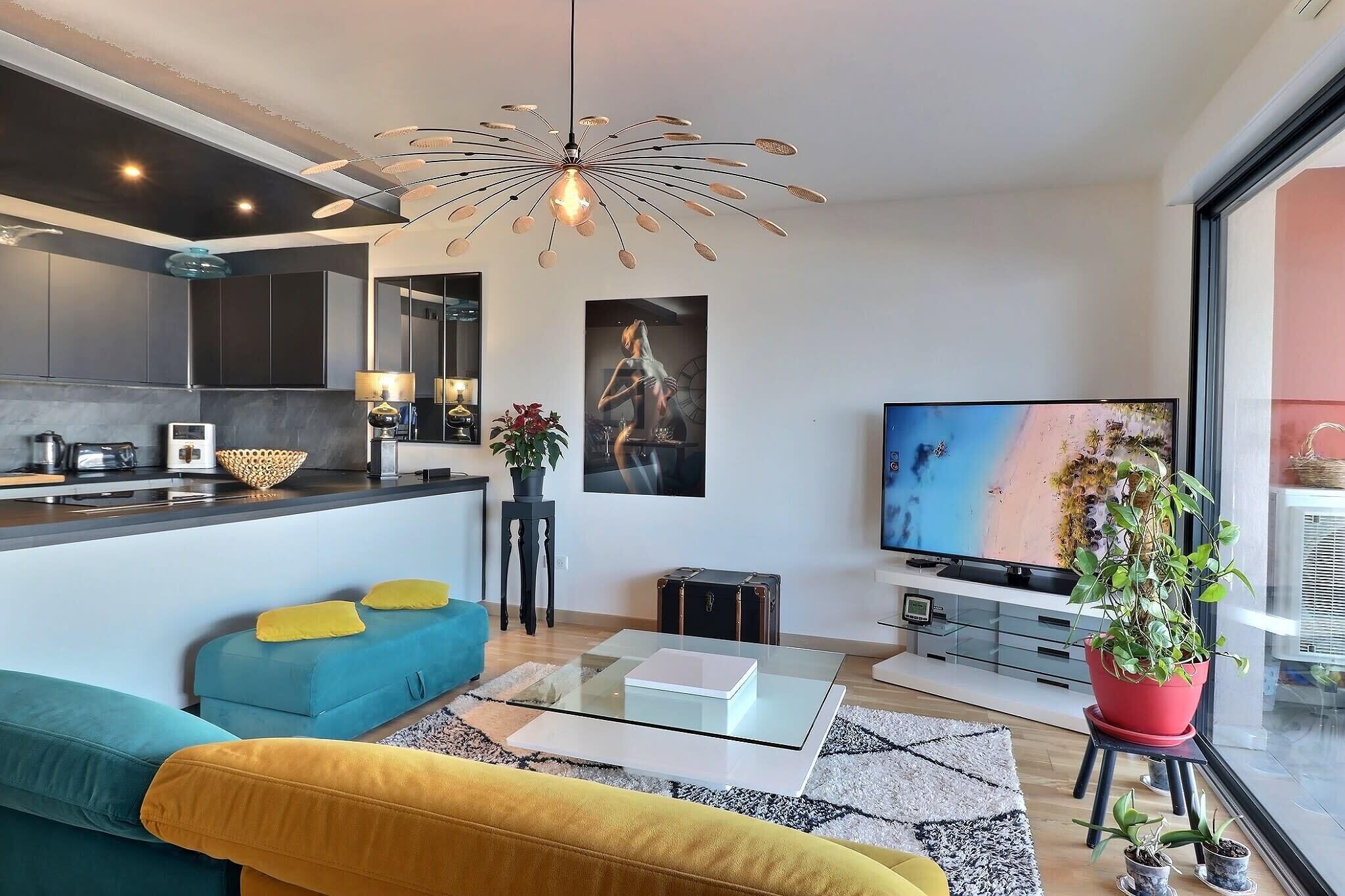 Una sala de estar moderna con sofá, mesa de centro, televisor y una lámpara de techo original.