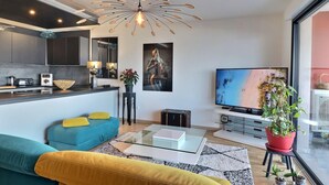 Een moderne woonkamer met een bank, salontafel, televisie en een bijzondere lamp.