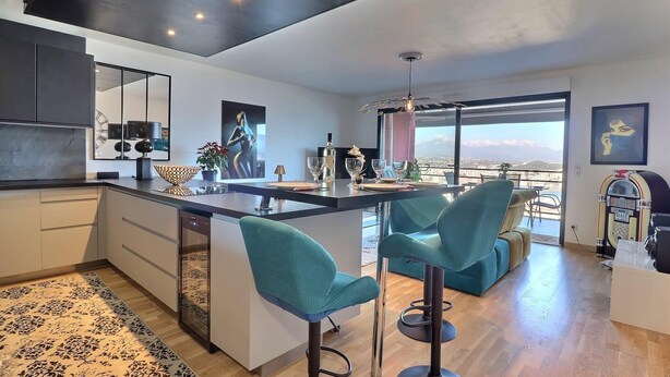 Een moderne keuken met een centraal eiland, barkrukken en een groot raam met uitzicht op de stad.