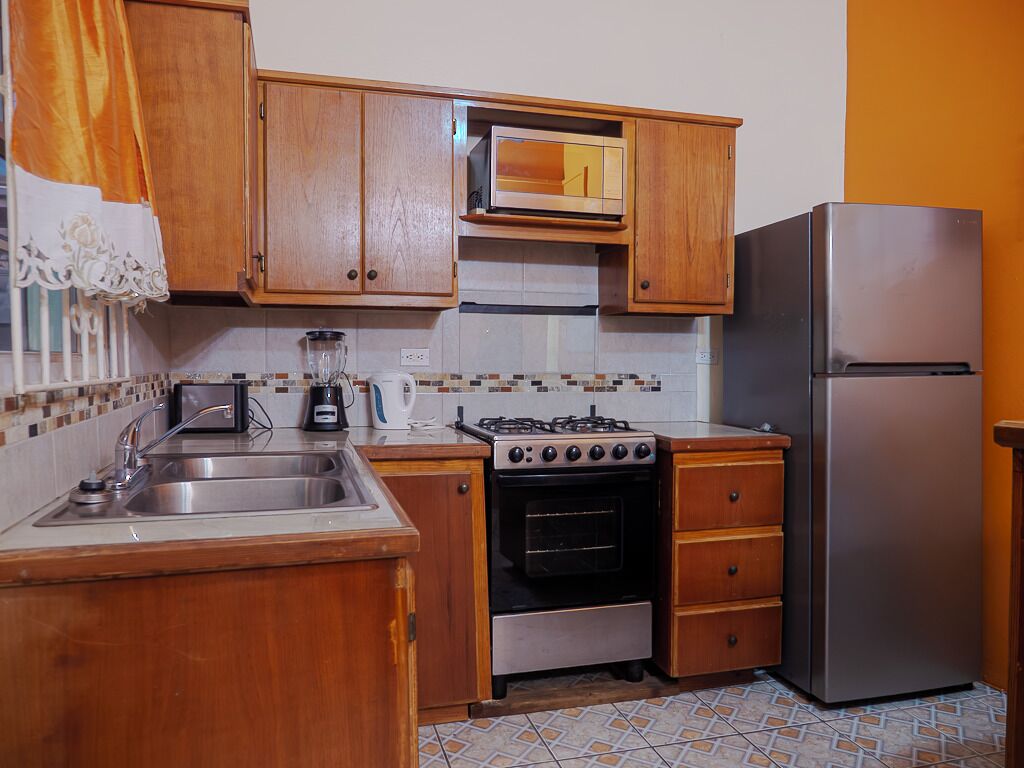 A kitchen with wooden cabinets, a stainless steel sink, a gas stove, an oven, and a refrigerator.
