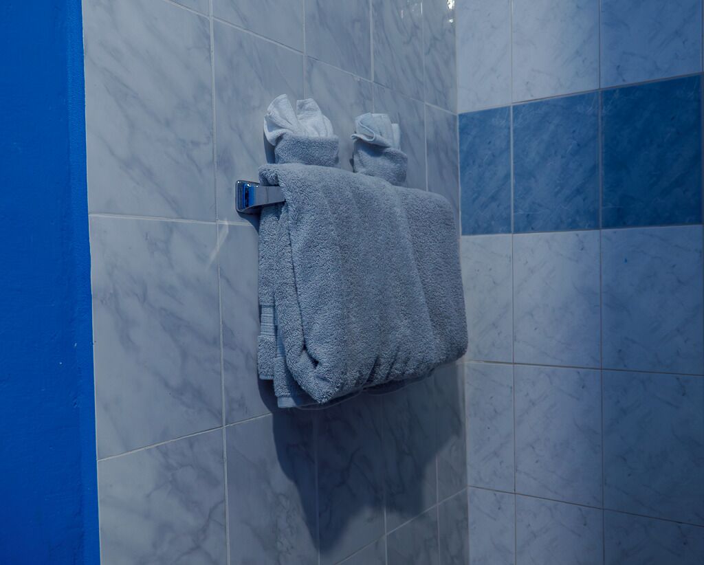 A bathroom with marble tiles, a towel rack with folded towels, and a blue accent wall.
