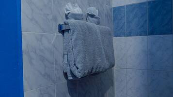 A bathroom with marble tiles, a towel rack with folded towels, and a blue accent wall.