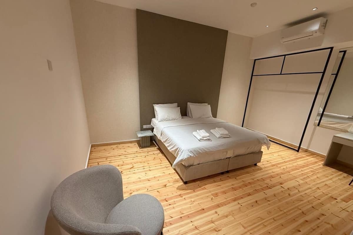 Ein modernes Hotelzimmer mit einem Bett, einem Sessel und Holzboden.