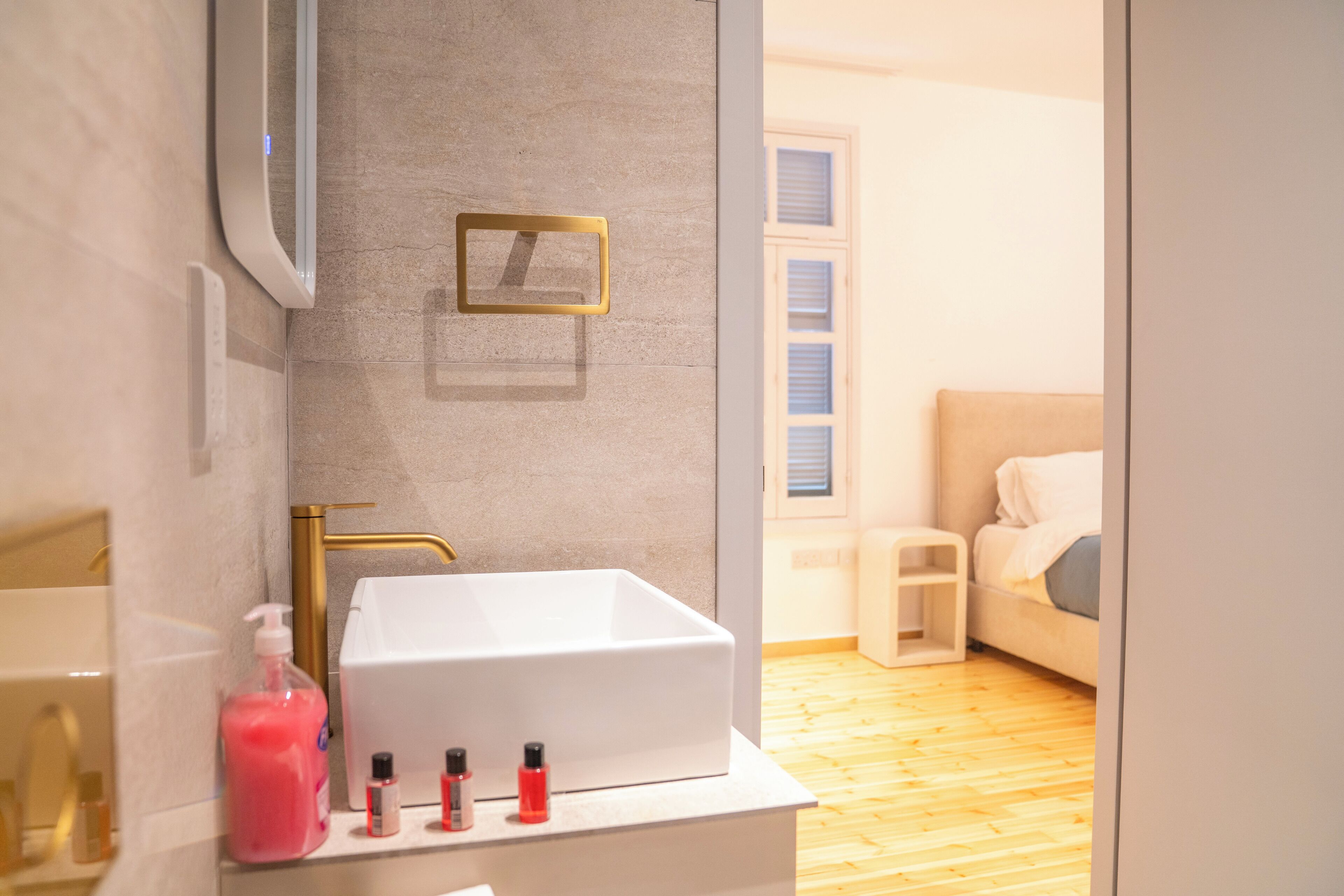 A bathroom with a white sink, a mirror, and a small shelf with toiletries.