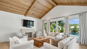 Ein geräumiges Wohnzimmer mit Holzboden, weißen Sofas, einem Couchtisch und einem Kamin.