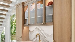 Eine Küche mit Holzausstattung, einer Marmor-Spritzschutzleiste und einem modernen Wasserhahn.